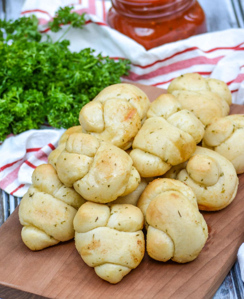 homemade garlic knots piled on a wooden cutting board