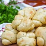 homemade garlic knots piled on a wooden cutting board