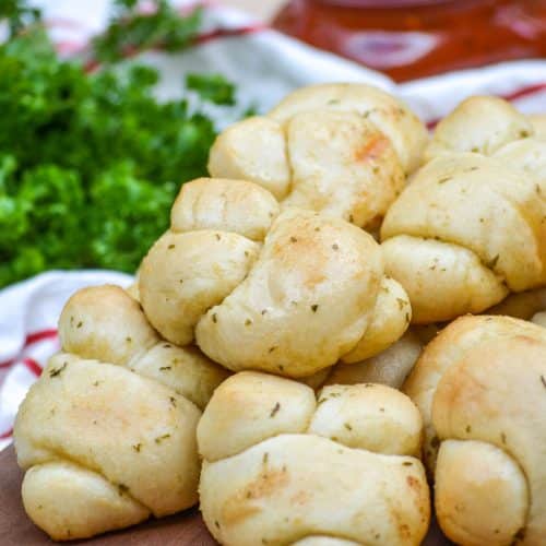 homemade garlic knots piled on a wooden cutting board