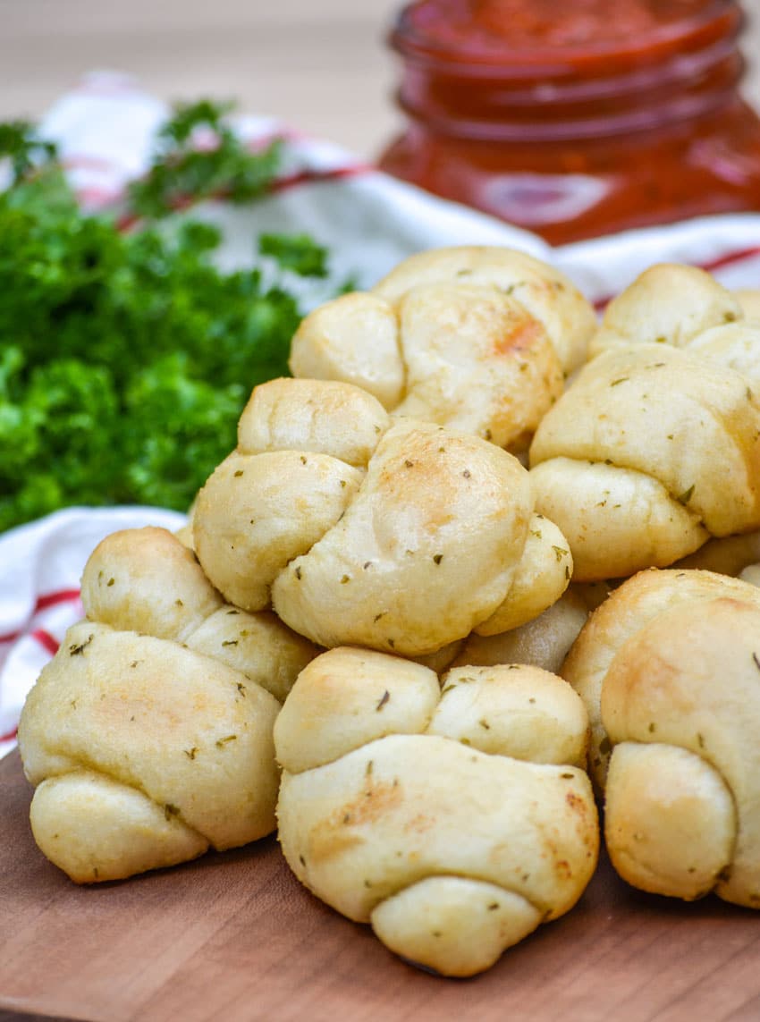 homemade garlic knots piled on a wooden cutting board