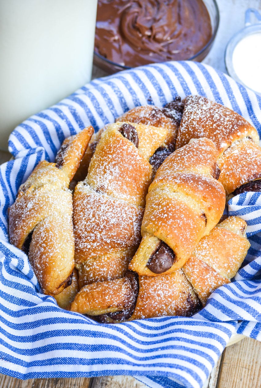 Nutella Crescent Rolls nutella crescent rolls sprinkled with powdered sugar in a cloth napkin lined basket