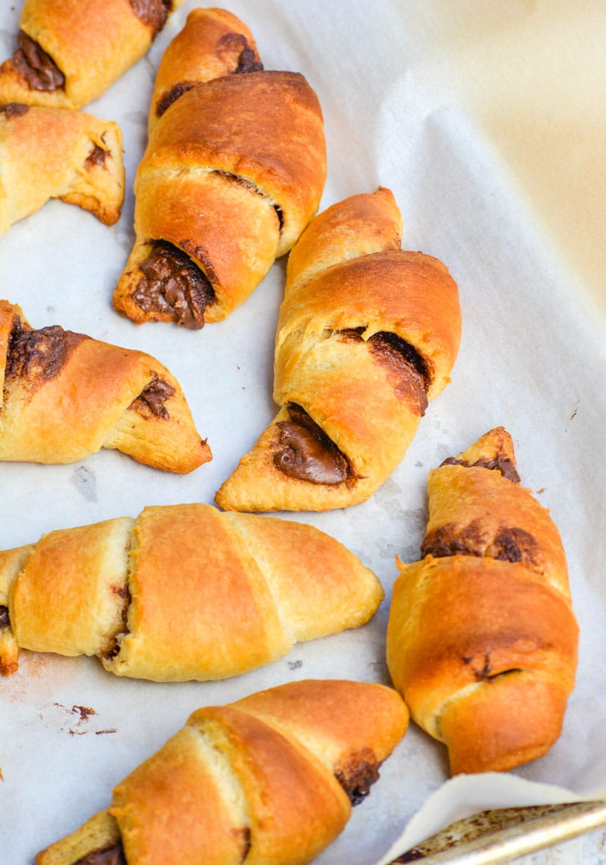 nutella stuffed crescent rolls on a white parchment paper lined baking sheet