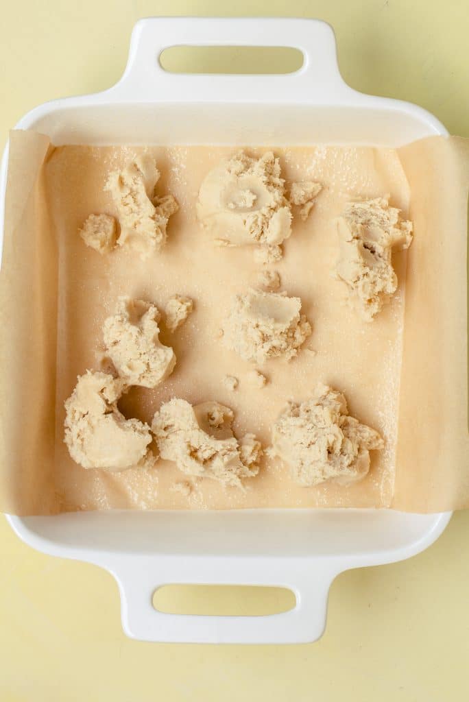 dollops of cookie dough in a parchment paper lined white baking dish