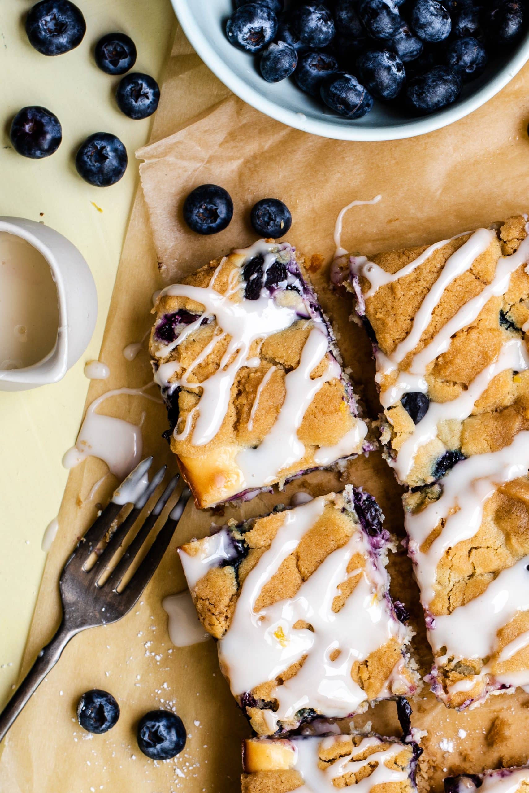 Blueberry Cheesecake Sugar Cookie Bars blueberry cheesecake sugar cookie bars on a wrinkled piece of brown parchment paper