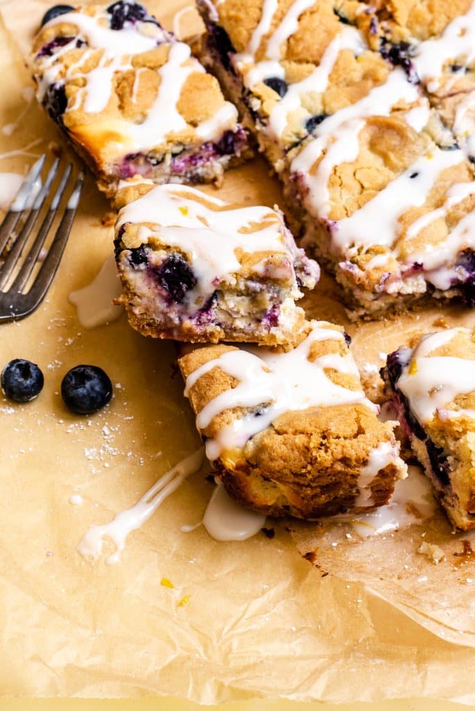 blueberry cheesecake sugar cookie bars on a wrinkled piece of brown parchment paper