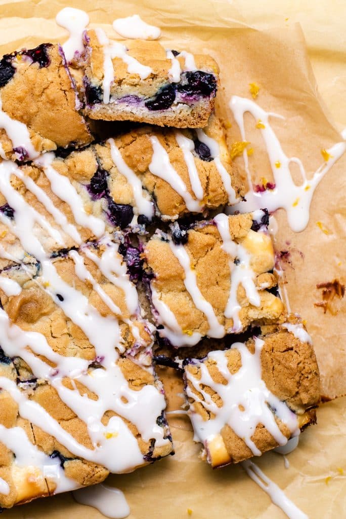 blueberry cheesecake sugar cookie bars on a wrinkled piece of brown parchment paper