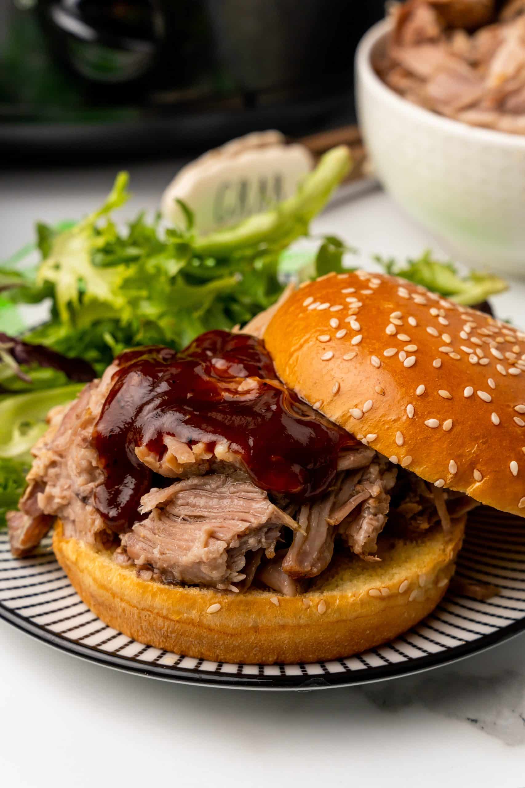 crockpot pulled pork topped with barbecue sauce on a sesame seed bun