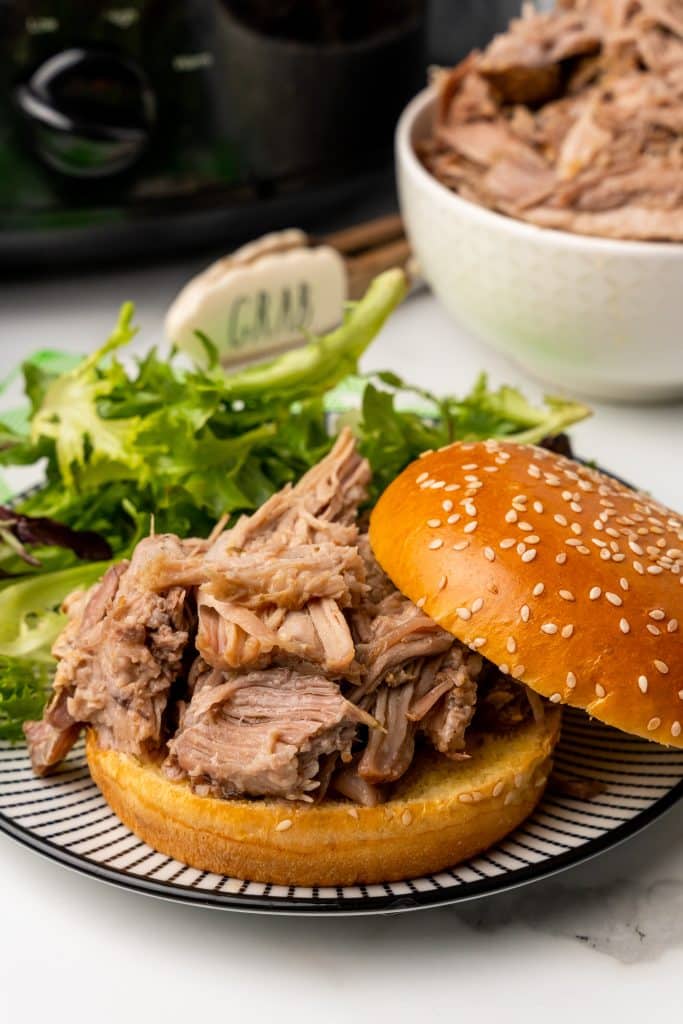 crockpot pulled pork shown served on a fluffy sesame seed son