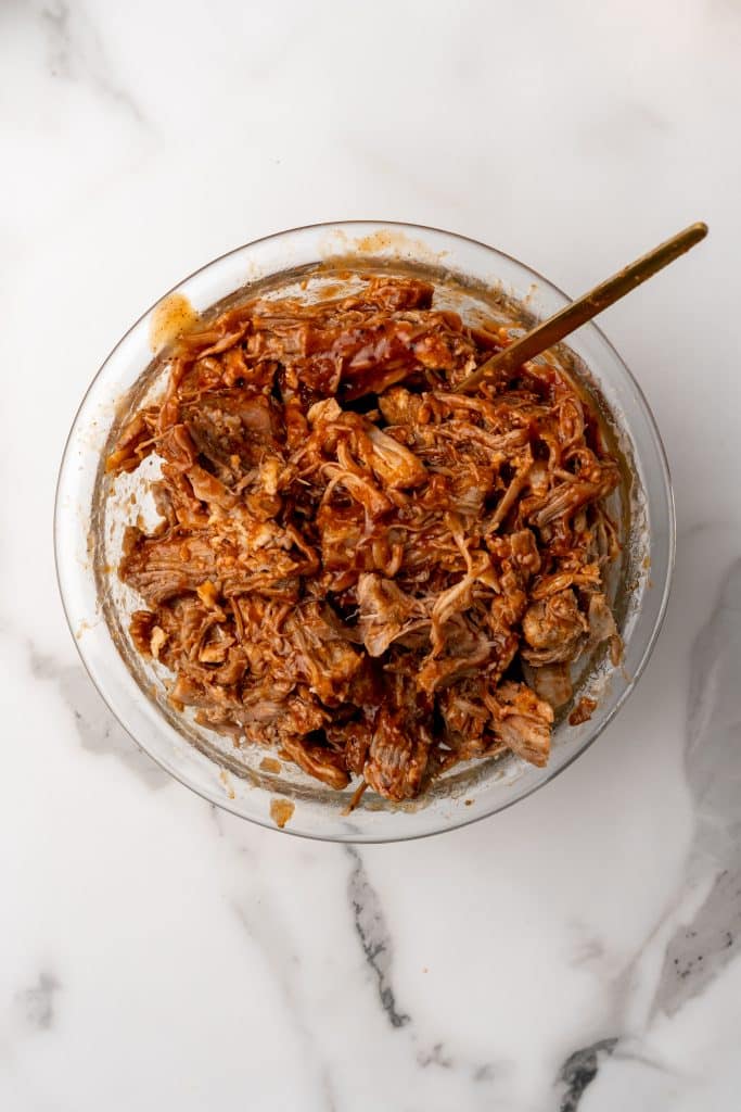 pulled pork mixed with barbecue sauce in a glass bowl