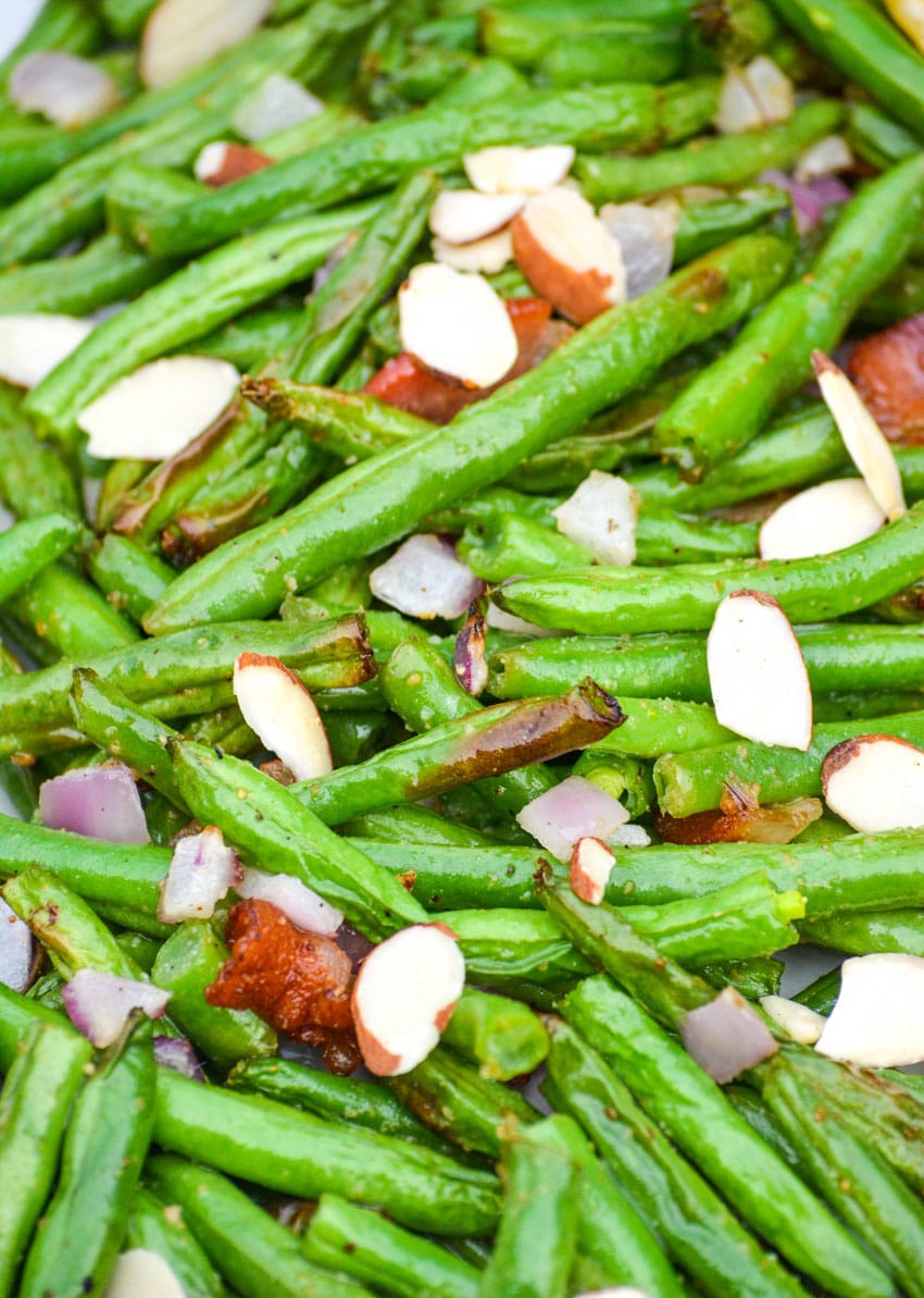 air fryer green beans on a white platter with slivered almonds and bacon crumbles