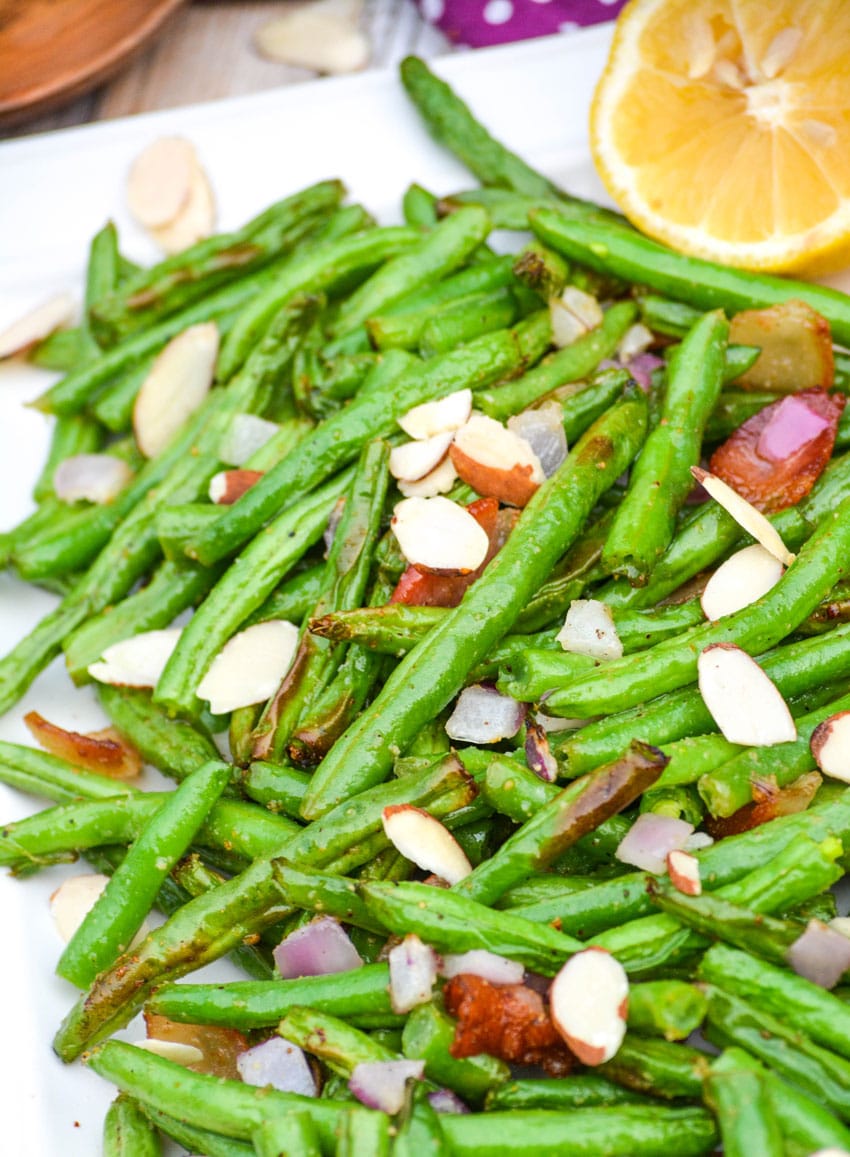 air fryer green beans on a white platter with slivered almonds and bacon crumbles