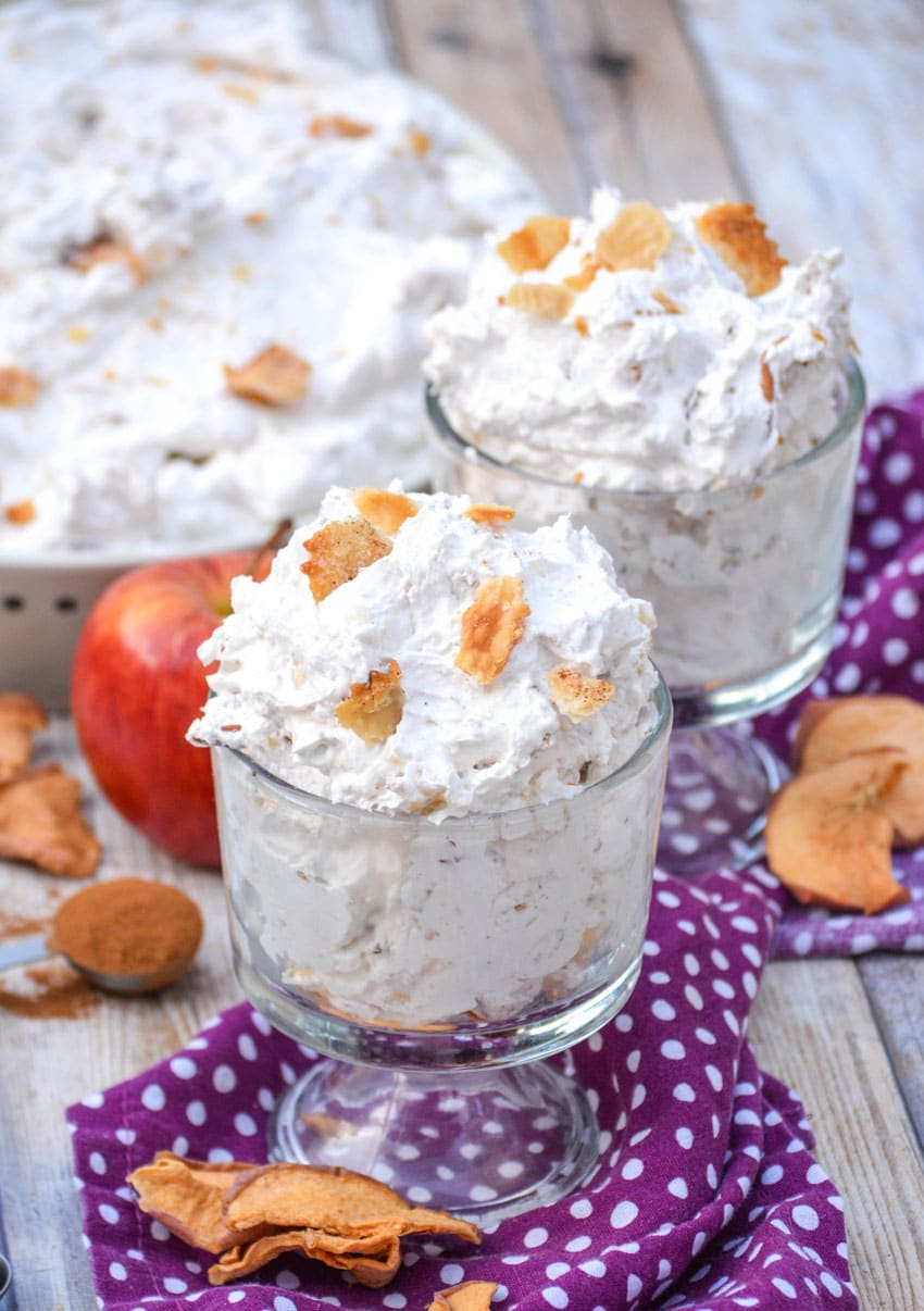 apple pie fluff salad in two glass jars topped with pieces of crumbled pie crust