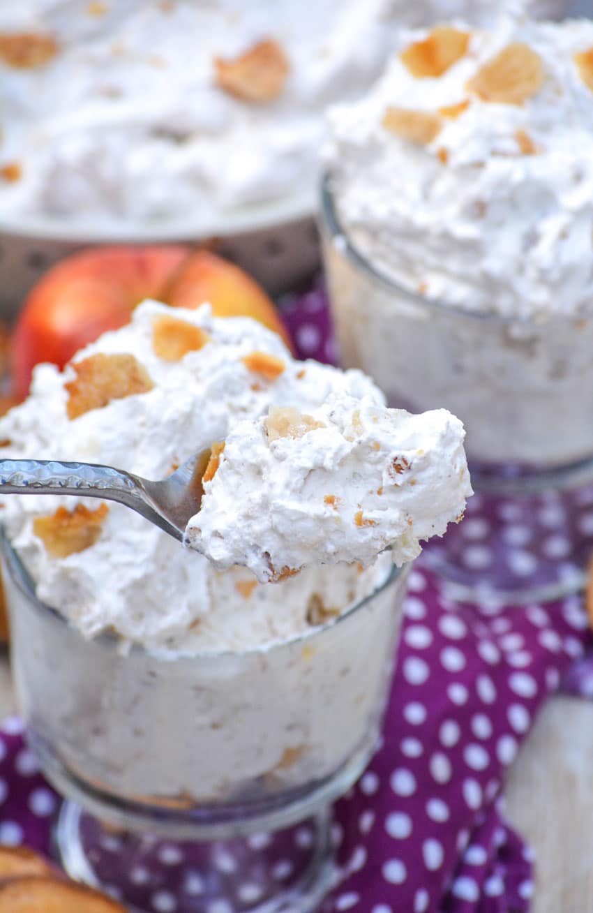 a silver spoon digging into a glass filled with apple pie fluff salad