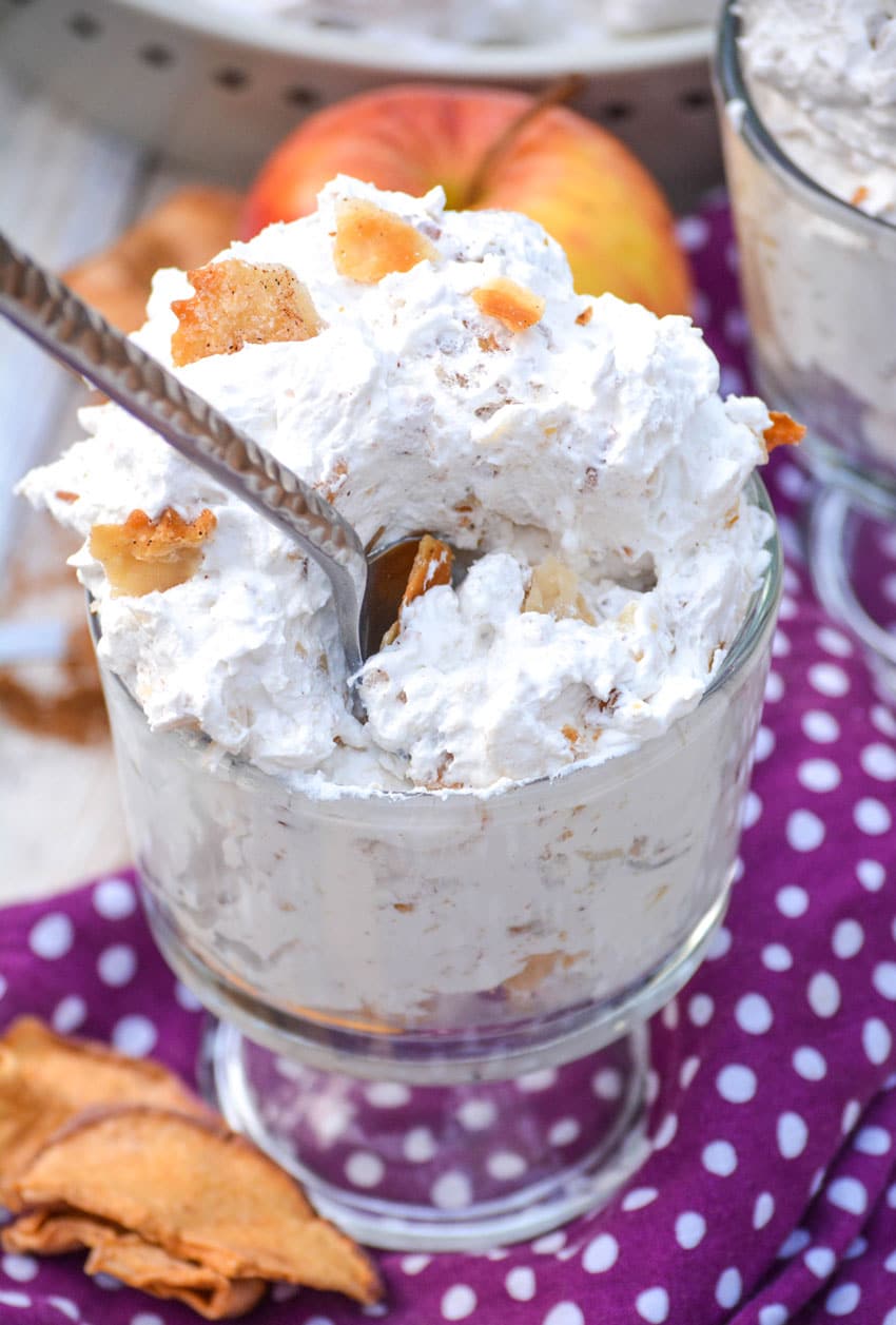 a silver spoon digging into a glass filled with apple pie fluff salad