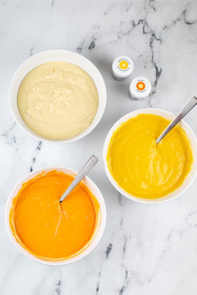 white bowls filled with white, yellow, and orange cake batter