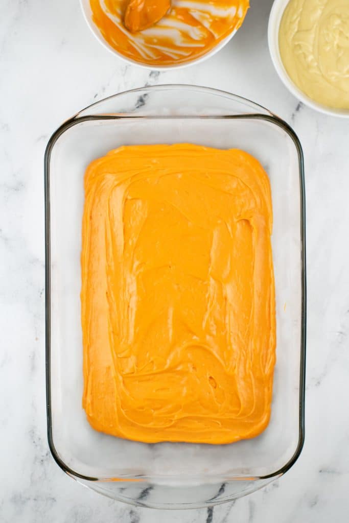 orange cake batter spread in a glass baking dish