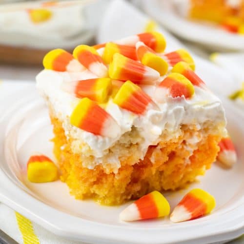 a slice of candy corn poke cake on a white plate
