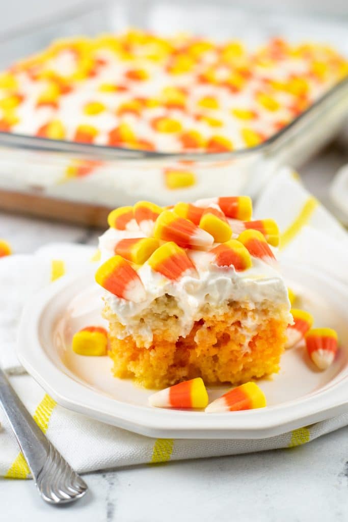 a slice of candy corn poke cake on a white plate