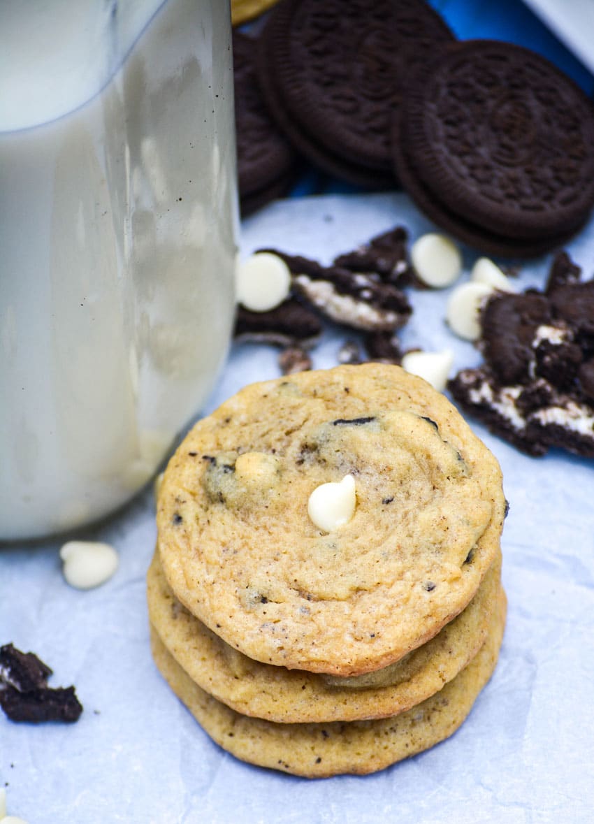 three cookies and cream pudding cookies stacked together next to a glass milk jar