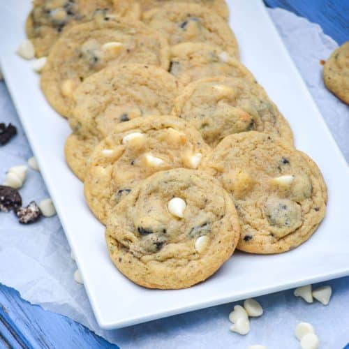 oreo cookies and cream pudding cookies with white chocolate chips arranged in two rows on a white serving platter