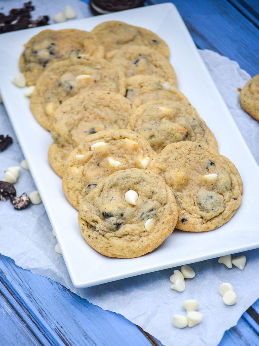 oreo cookies and cream pudding cookies with white chocolate chips arranged in two rows on a white serving platter