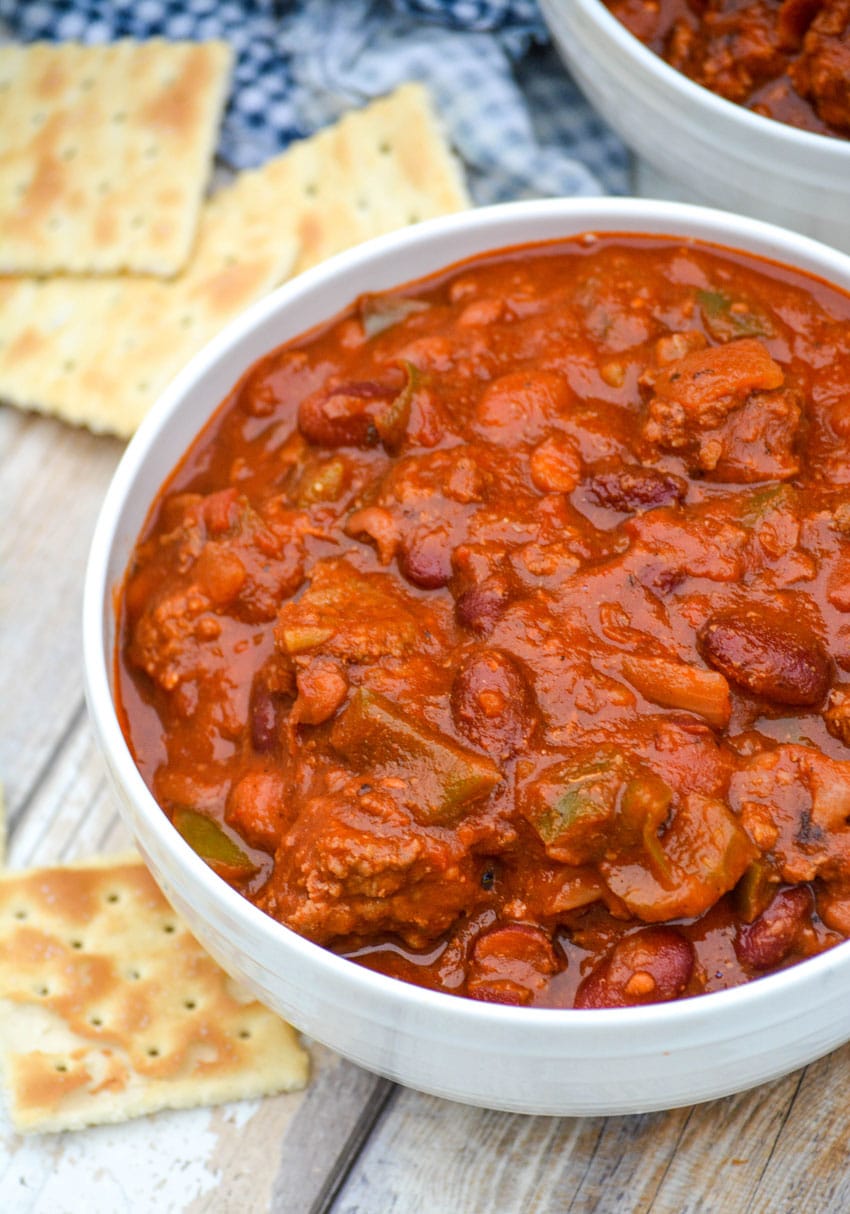 a white bowl filled with copycat wendy's chili with saltine crackers on the side