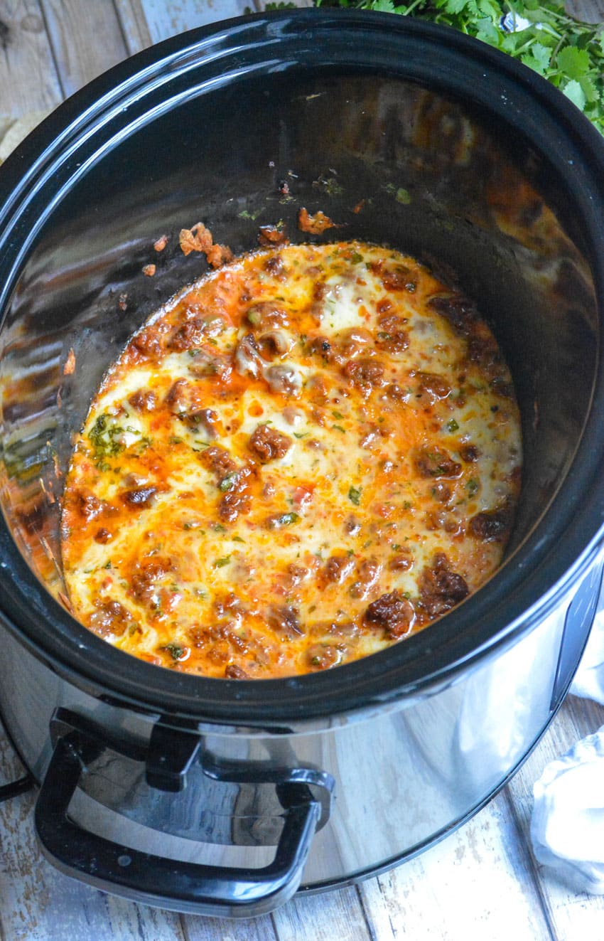 slow cooker queso fundido dip in the black bowl of a crockpot