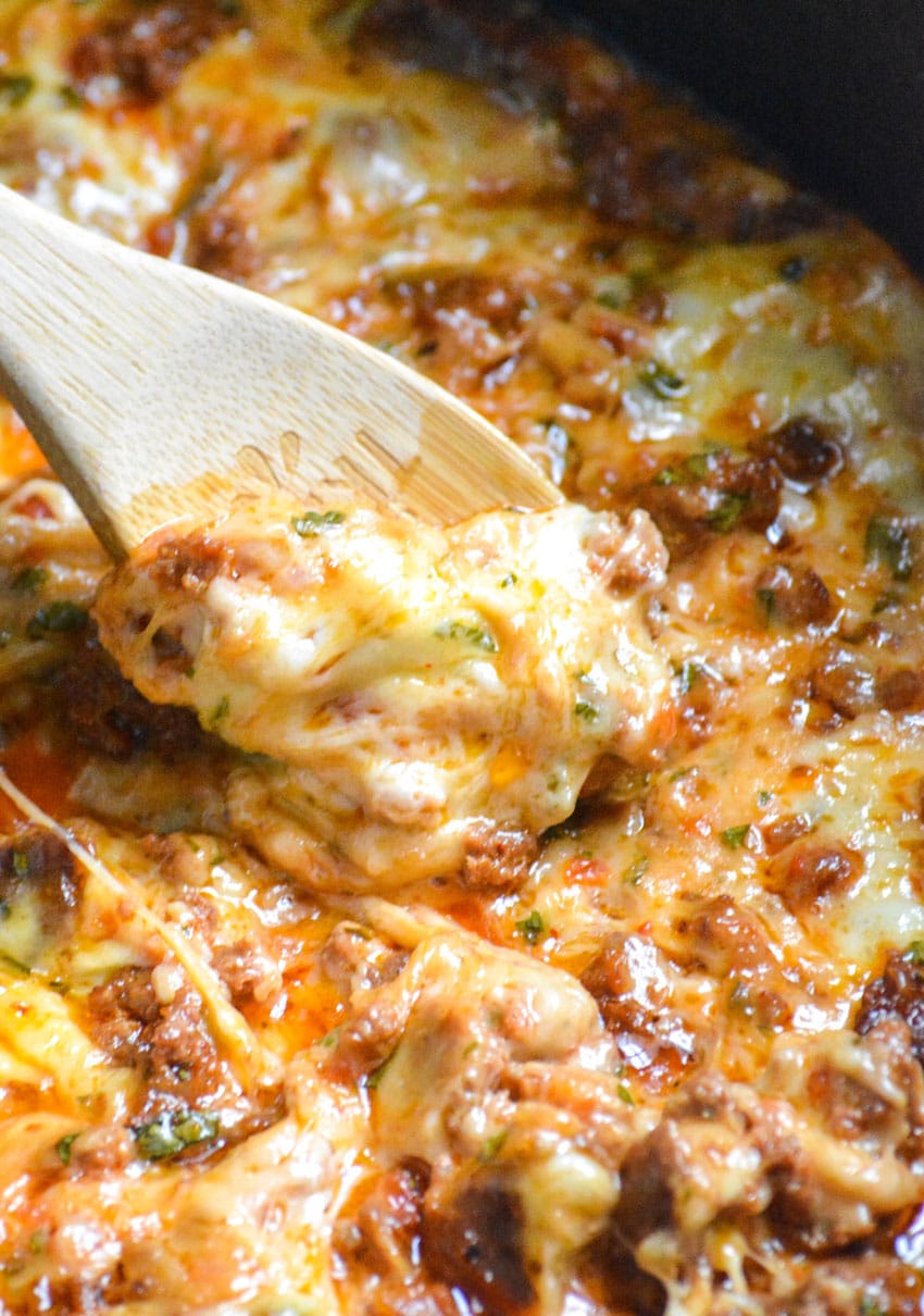 a wooden spoon with a scoop of cheesy slow cooker queso fundido on it