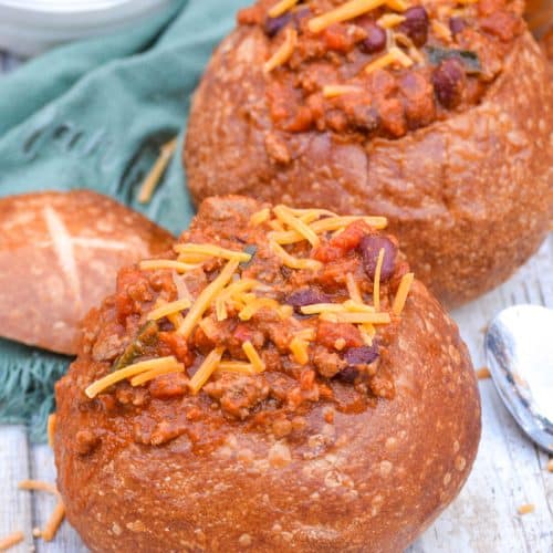 pumpkin chili in a bread bowl topped with shredded cheddar cheese