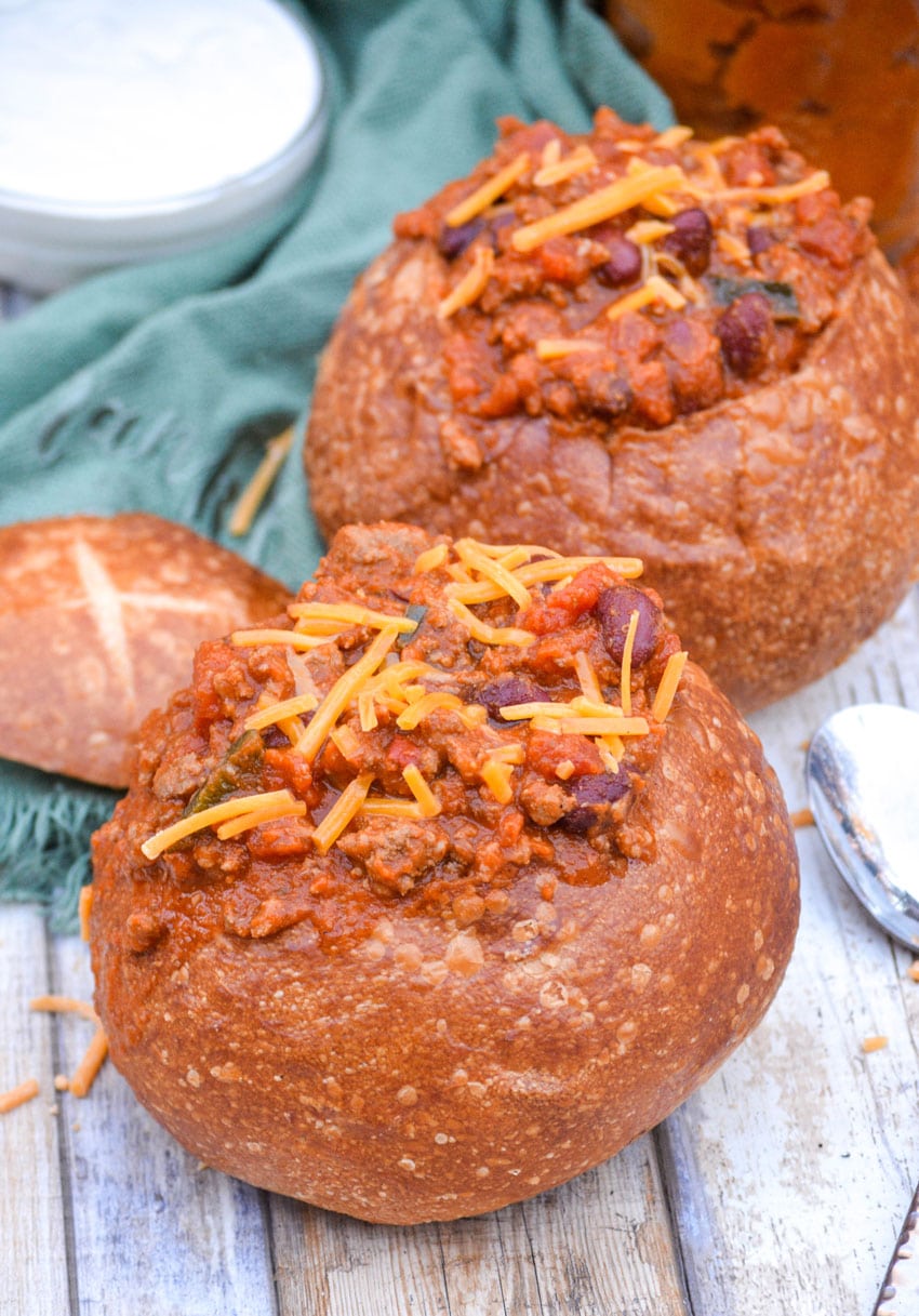pumpkin chili in a bread bowl topped with shredded cheddar cheese