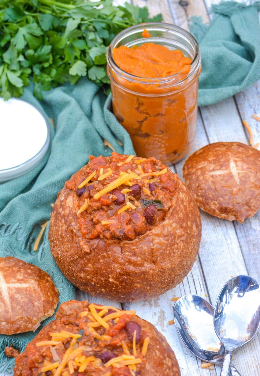 pumpkin chili in a bread bowl topped with shredded cheddar cheese