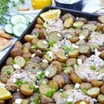 sheet pan greek chicken and potatoes topped with sliced green onions and crumbled feta cheese