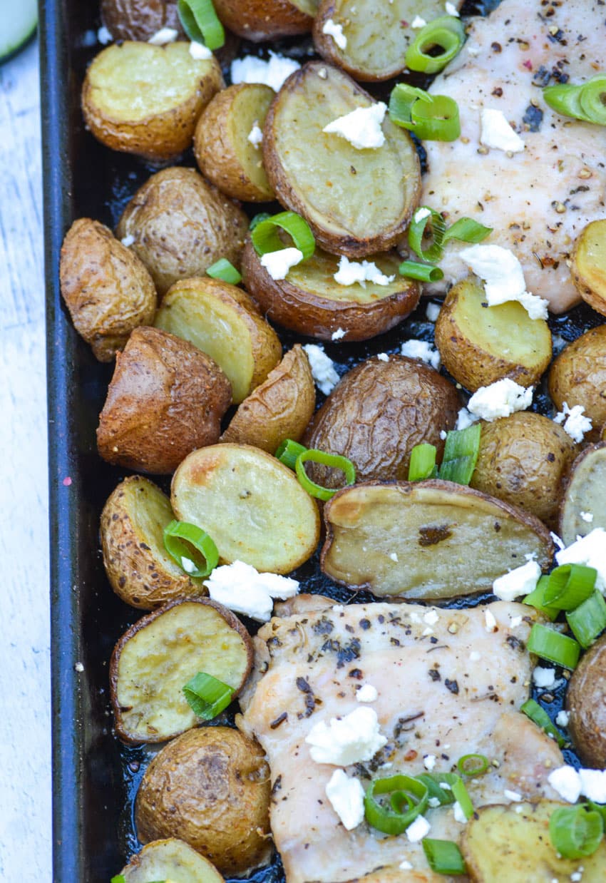 lemon feta sheet pan chicken and potatoes topped with sliced green onions and crumbled feta cheese