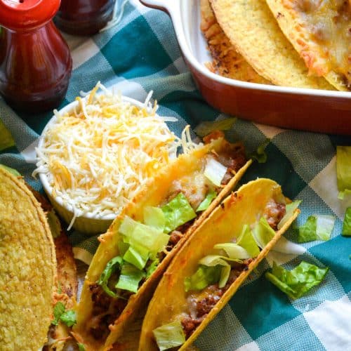 lettuce topped sloppy joe tacos sitting on a blue and white checkered cloth napkin