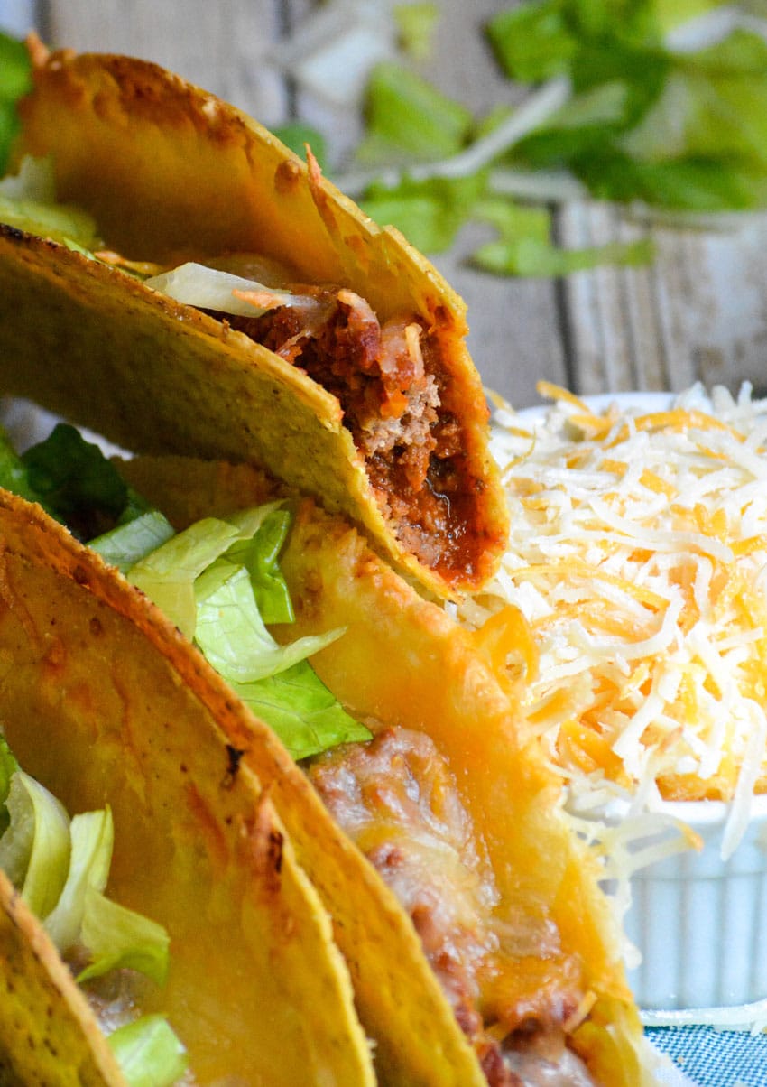 a bitten sloppy taco held up to reveal the juicy meat filling inside the crispy shell