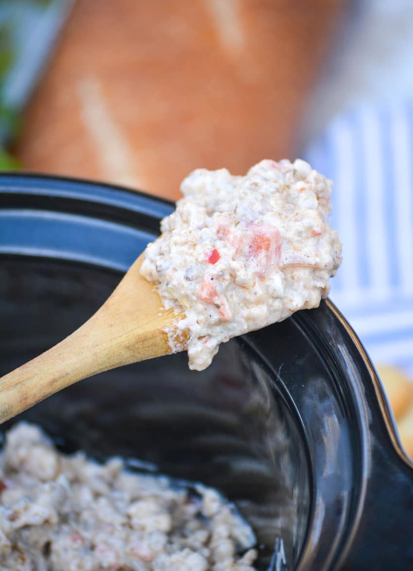3 ingredient sausage dip on a wooden spoon resting on the edge of a black crockpot