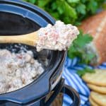 3 ingredient sausage dip on a wooden spoon resting on the edge of a black crockpot