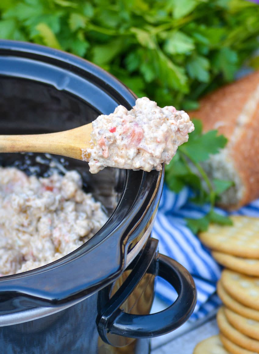 3 ingredient sausage dip on a wooden spoon resting on the edge of a black crockpot