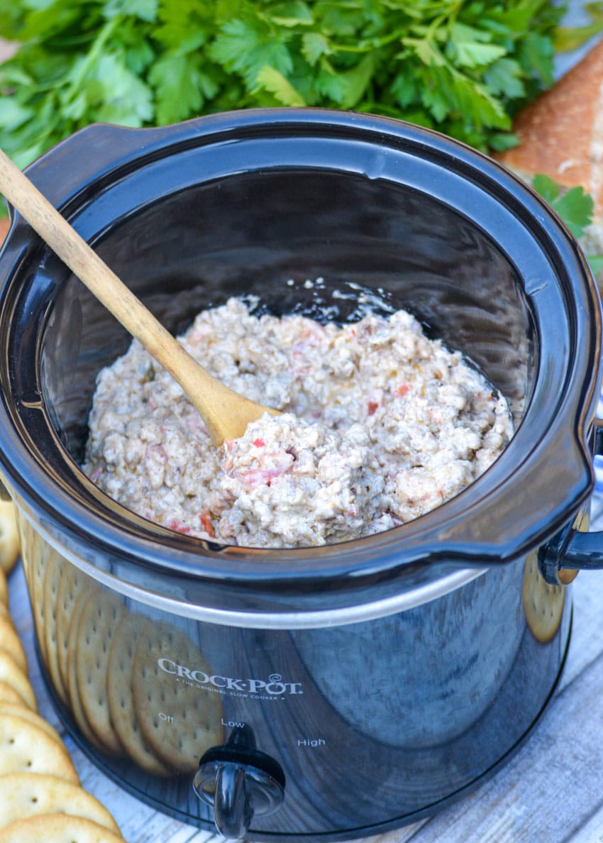 a wooden spoon stuck in a crockpot filled with 3 ingredient sausage dip