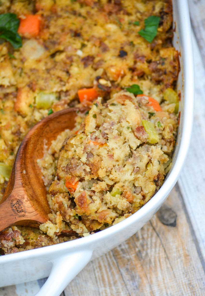 homemade stuffing hack using stove top mix being scooped out of a white casserole dish by a wooden serving spoon