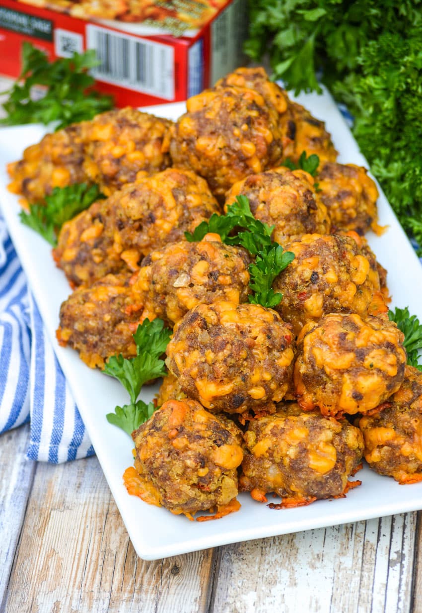 cheesy sausage stuffing balls on a white platter with fresh parsley leaves