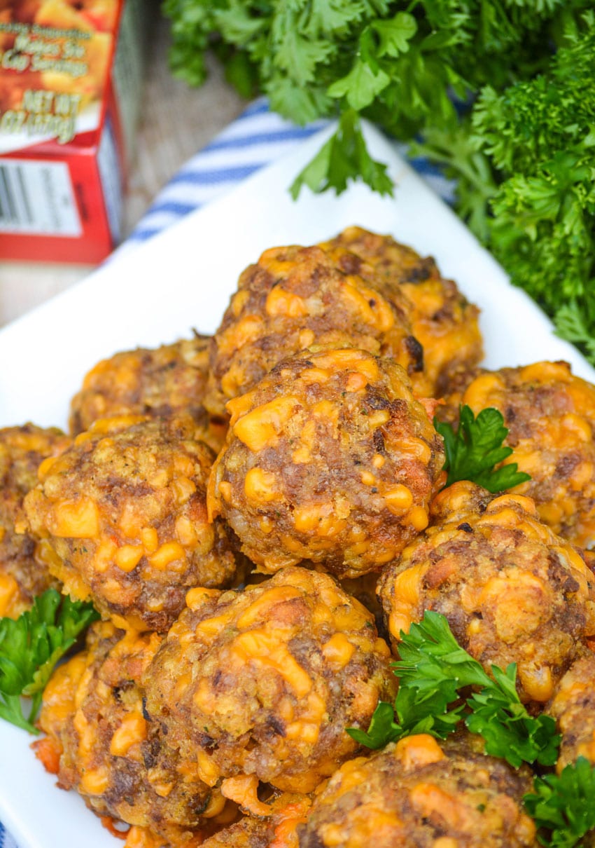 three ingredient sausage balls on a white platter with fresh parsley leaves