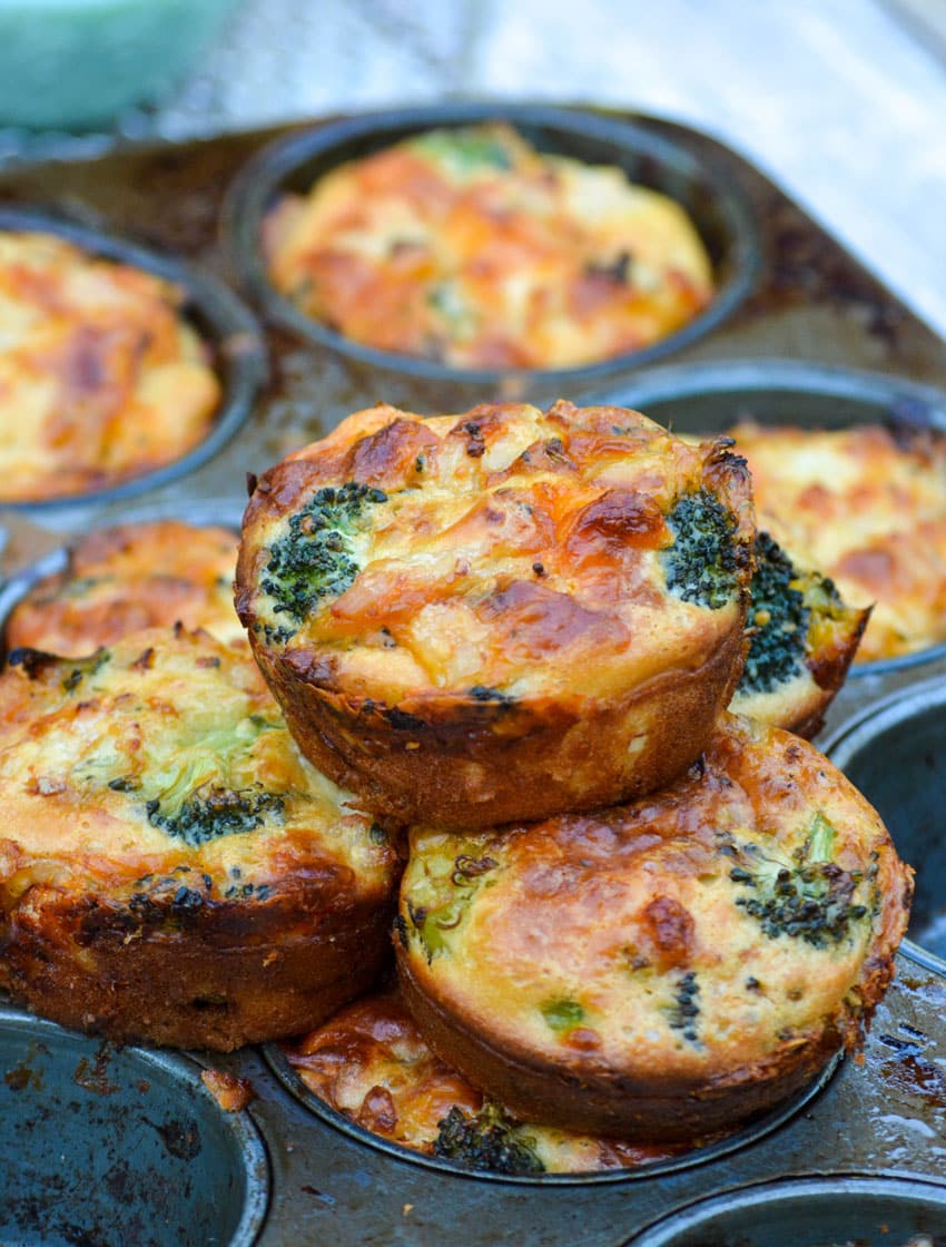 mini chicken broccoli and cheddar pies stacked on a metal muffin tin