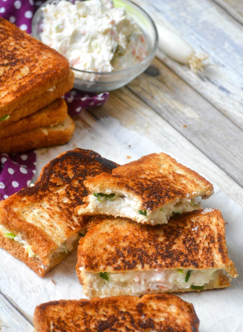 cut halves of crab rangoon grilled cheese sandwiches on a wooden table