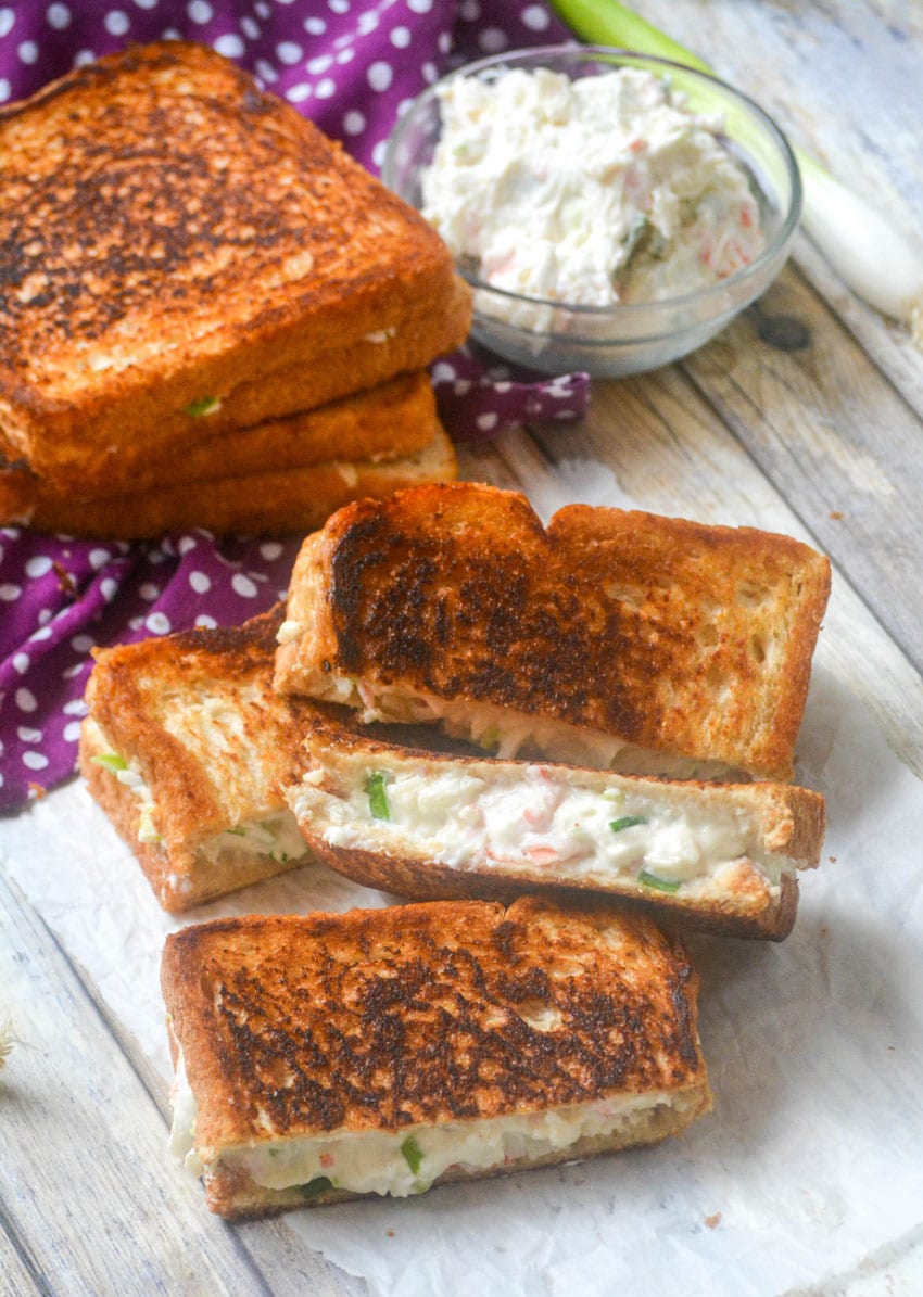 cut halves of crab rangoon grilled cheese sandwiches on a wooden table
