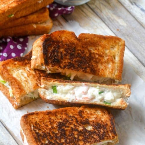cut halves of crab rangoon grilled cheese sandwiches on a wooden table