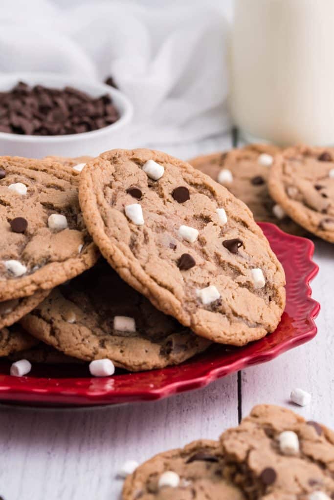 marshmallow and chocolate chip topped hot cocoa cookies piled on a red plate