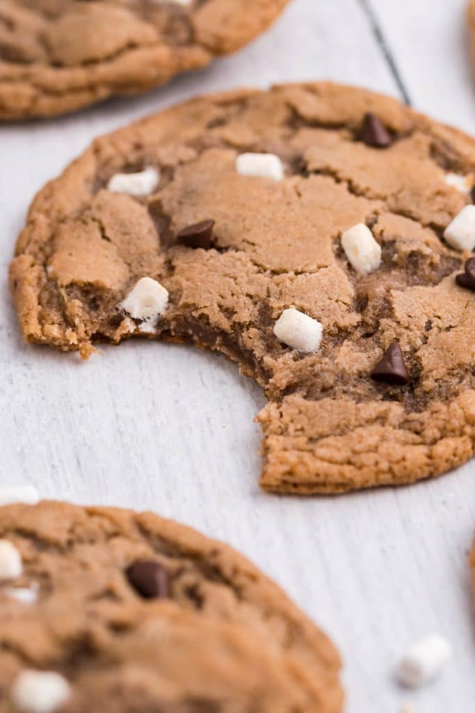 a hot cocoa cookie with a bite out of it resting on a wooden table