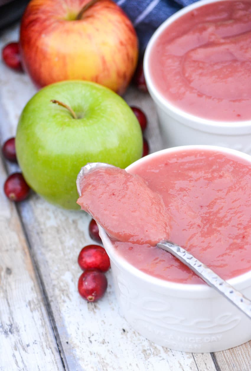 a spoon resting on the edge of a white ramekin filled with instant pot cranberry applesauce