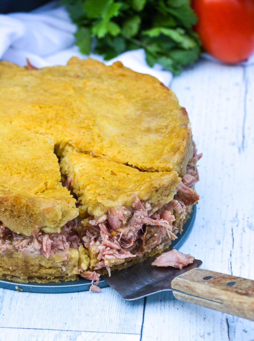 a spatula removing a single slice of tamale pork pie from the whole pie